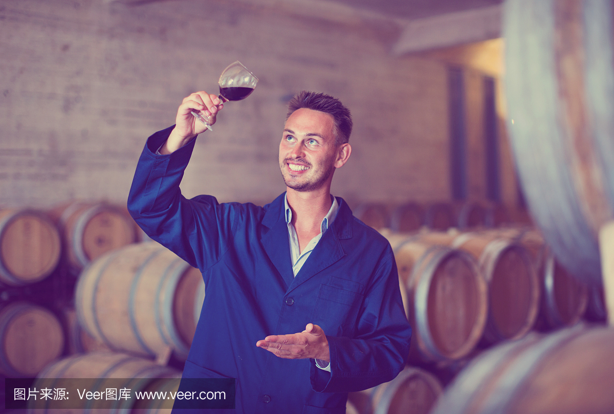 牢房里穿著制服的男釀酒師手里拿著一杯酒